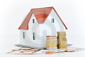 House ownership concept â€“ a model house on a pile of coins