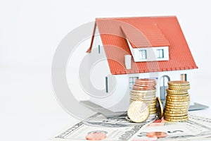 House ownership concept â€“ a model house on a pile of coins