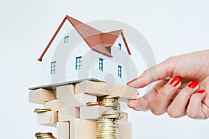 House ownership concept â€“ a model house on a pile of coins