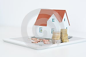 House ownership concept â€“ a model house on a pile of coins
