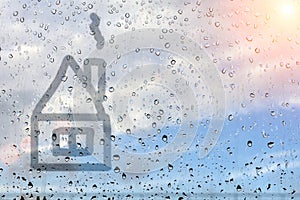 House painted on misted glass. Window glass with raindrops against the blue sky