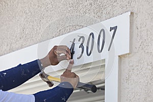 House Painter Contractor Nails Address Numbers to House Facade