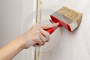 House-painter, hand holds a brush, draws and primed a wall. close-up. The concept of repair and decoration, painting, repair