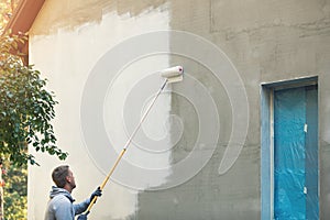 House painter painting building exterior with roller