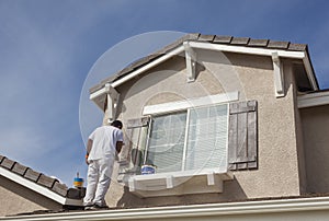 House Painter Painting the Trim And Shutters of Home