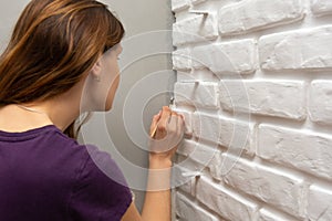 A house painter tends to paint a gray corner of the wall with a small tassel