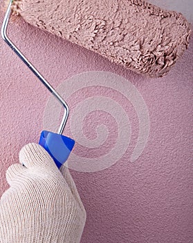 House painter using paint roller, painting wall