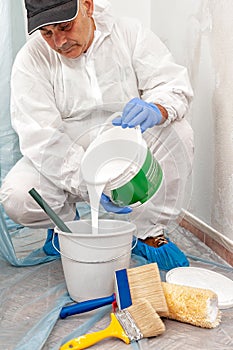 House painter at work prepares white paint