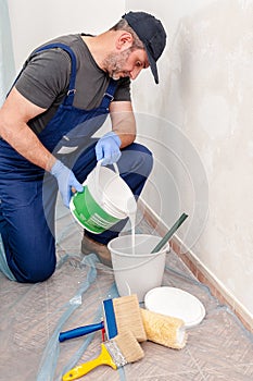 House painter at work prepares white paint