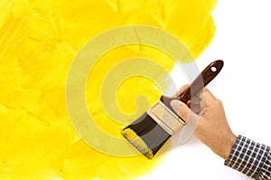 House painting and decorating - unfinished painted yellow wall with man holding paintbrush. Copy space.