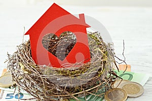 House paper with heart in nest on money background - Love for home, home insurance concept