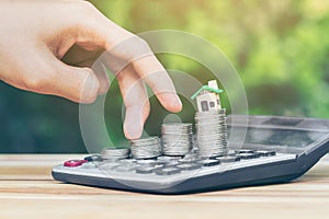 House placed on coins Men`s hand is planning savings money of coins to buy a home