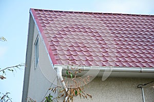 House with plaster walls, red metal roof and white plastic rain