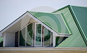 The house with plastic windows and a green roof of corrugated sh