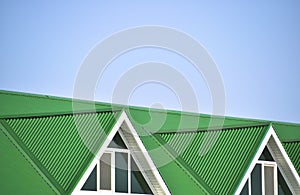 The house with plastic windows and a green roof of corrugated sheet