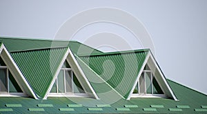 The house with plastic windows and a green roof of corrugated sheet. Green roof of corrugated metal profile and plastic windows.