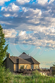 House with porch and spacious balcony viewed against blue sky and puffy clouds