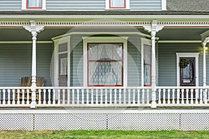 House with porch and white railings. White veranda and railing posts, brown boards, elevated above ground