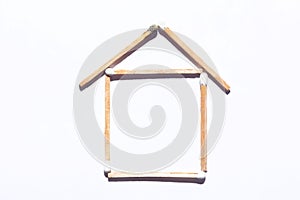 house and real estate concept: abstract house made with matches with one burnt match isolated on white background with copy spaye