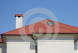 House red ceramic tiles rooftop with attic skylight window, rain gutter pipeline and white brick facade walls