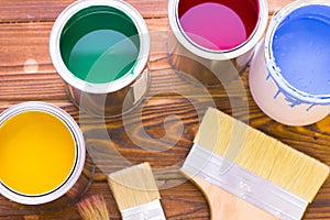 House renovation concept, colorfull paint cans and paintbrushes on dark wooden background