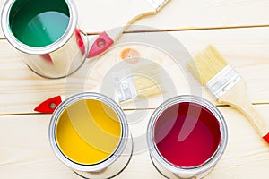 House renovation concept, colorfull paint cans and paintbrushes on wooden background