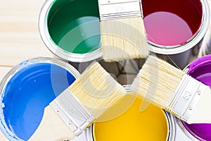 House renovation concept, colorfull paint cans and paintbrushes on wooden background