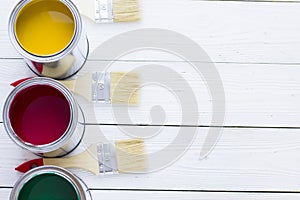 House renovation concept, colorfull paint cans and paintbrushes on wooden background