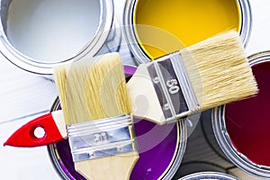 House renovation concept, colorfull paint cans and paintbrushes on wooden background