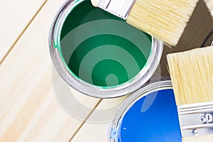 House renovation concept, colorfull paint cans and paintbrushes on wooden background photo