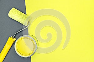 House renovation concept. paint roller and can of yellow paint on gray and yellow background.