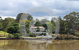 House on the river in Queensland Australia with palms and tall gumn trees under a stormy sky in spring