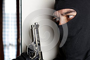 House robbery by man in a black hoodie and black mask and gun.