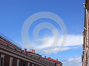 House roof and blue sky with clouds. Look up. Drainpipes