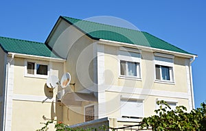 House roof with metal roof shingles, rolling shutters and roof gutter pipeline outdoors.