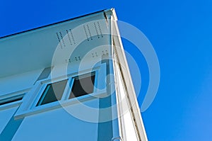 House roof with rain gutter of roof top house and large windows on blue sky background, New modern building