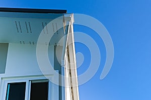 House roof with rain gutter of roof top house and large windows on blue sky background, New modern building