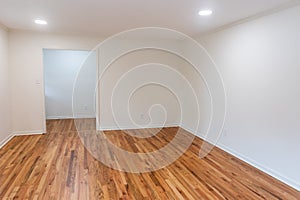 A house for sale with an empty white living room or den of a newly renovated and painted house with dark hardwood floors