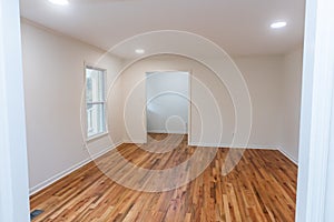 A house for sale with an empty white room of a newly renovated and painted house with dark hardwood floors