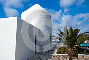 House by sea in Mykonos, Greece. Whitewashed building and palm on sunny blue sky. Typical house architecture and design