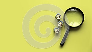 House searching concept. House inspection. Miniature house with magnifying glass over a yellow background with copy space