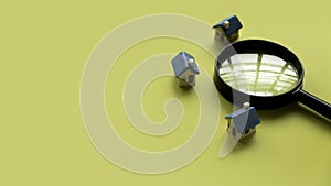 House searching concept. House inspection. Miniature house with magnifying glass over a yellow background with copy space