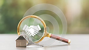 House shape keychain and magnifying glass, nature background, home search concept, real estate investment, negotiation success,