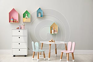 House shaped shelves and little table with chairs in children`s room. Interior