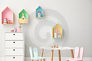 House shaped shelves and little table with chairs in children`s room. Interior design