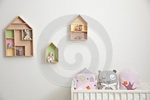 House shaped shelves with toys and crib in nursery. Baby room interior design