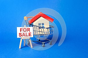 House in a shopping cart and an easel sign labeled for sale. Buying and selling real estate, hot offers and property valuation