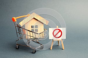 House in the shopping cart and the sign of the ban NO. Inaccessible and expensive housing. Seizure and freezing of assets