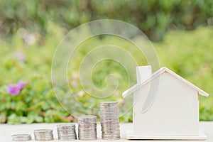 House and stack coins on blurred green natural background. Property investment and house mortgage financial concept