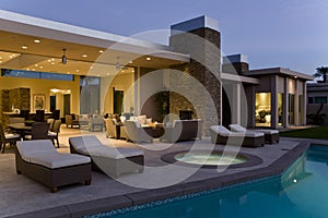 House With Sunloungers On Patio By Pool At Dusk